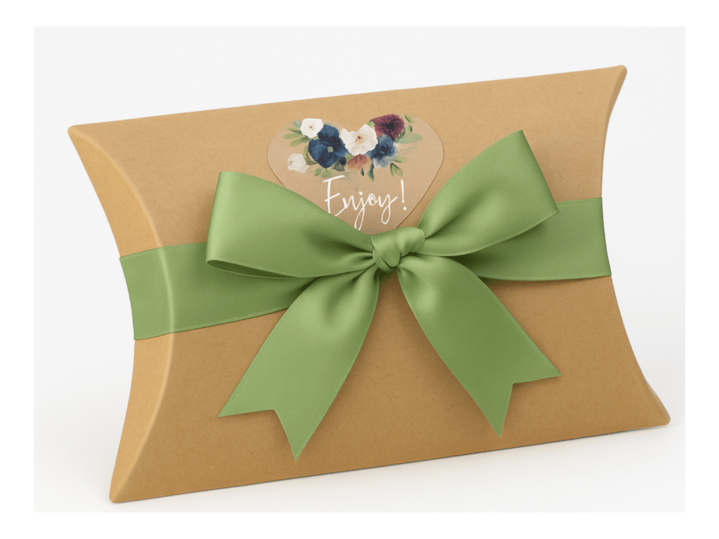 Brown pillow-shaped gift box with green satin ribbon and floral heart tag labeled "Enjoy!"